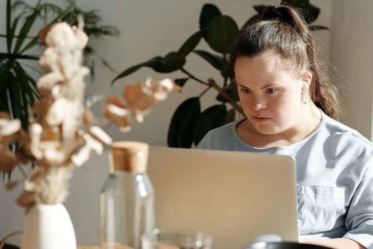 young woman with downs syndrome sits at laptop