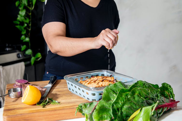 Person squeezing lemon on fish