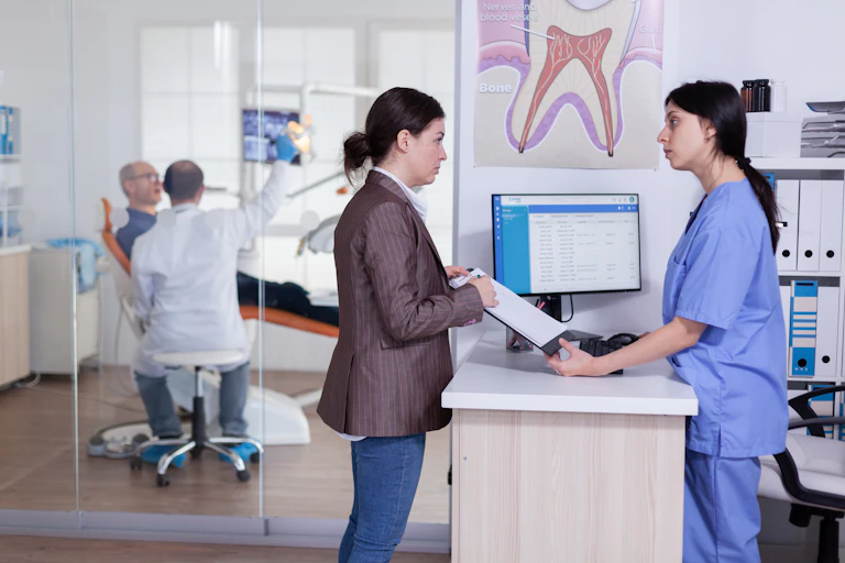 A patient speaks with a nurse in a dental office.
