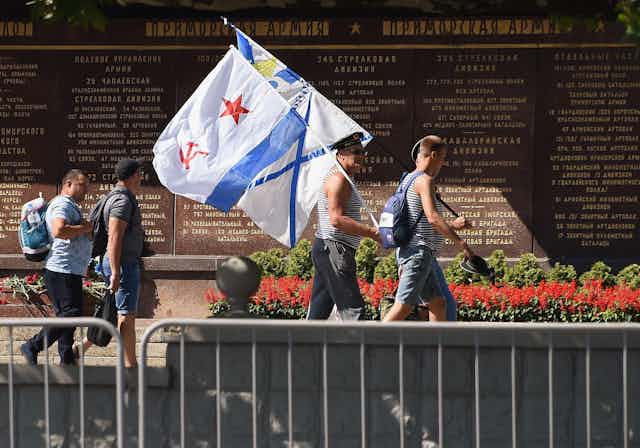 Men carrying flags in front of a memorial.