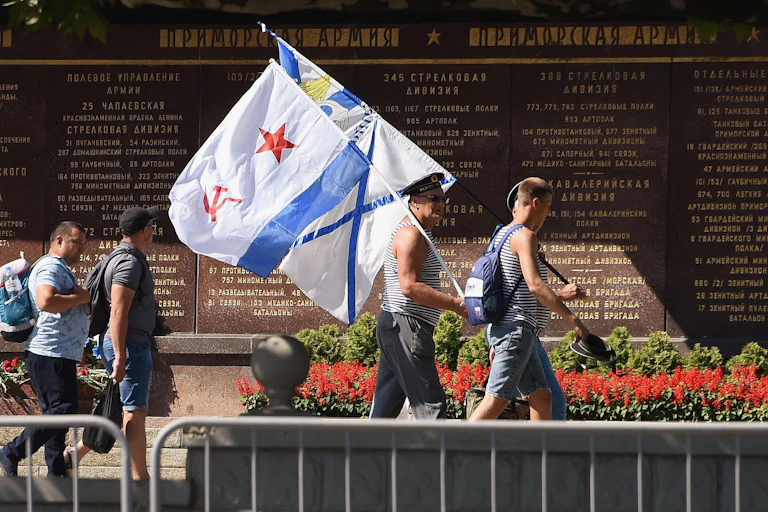 Men carrying flags in front of a memorial.