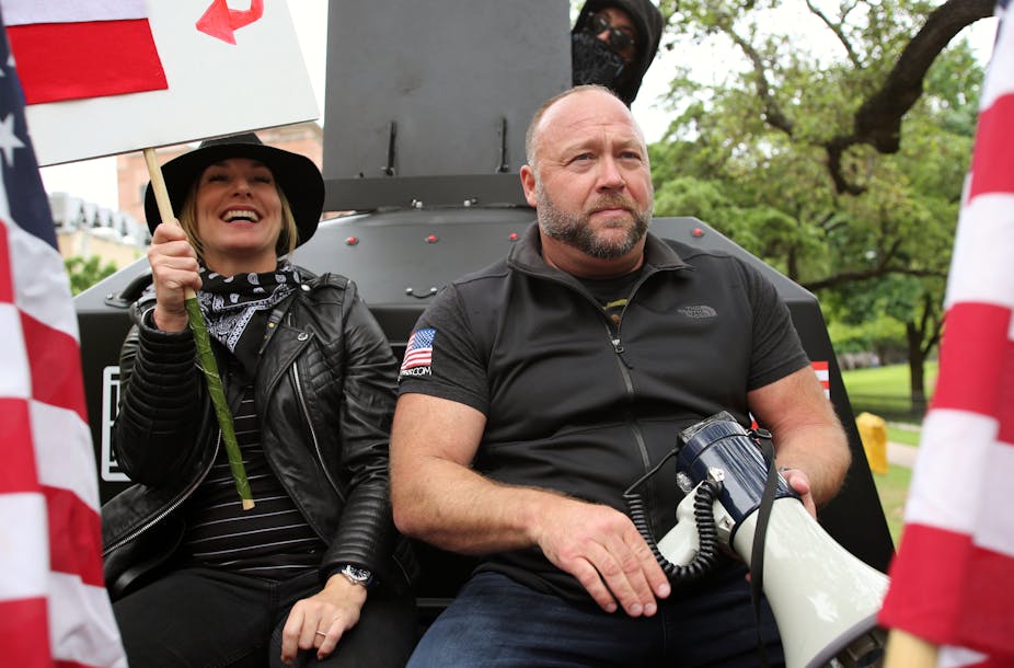 Alex Jones, with his wife Erika Wulff Jones, sits in the bed of an armored truck 