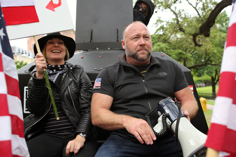 Alex Jones, with his wife Erika Wulff Jones, sits in the bed of an armored truck
