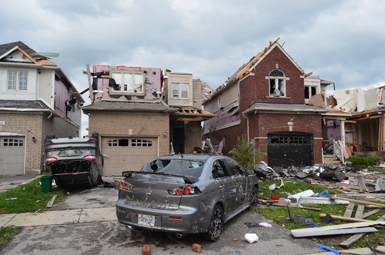 Damaged cars are seen next to the remains of houses damaged by a tornado.