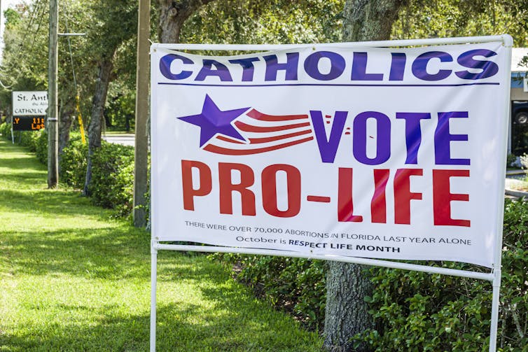 A sign reads 'Catholics vote pro-life', written in red, white and blue.
