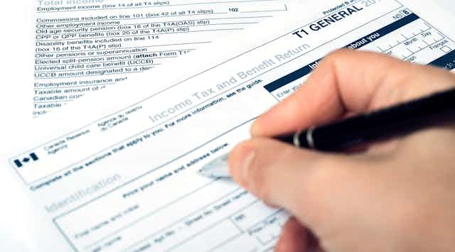 A hand filling out a Canadian income tax form