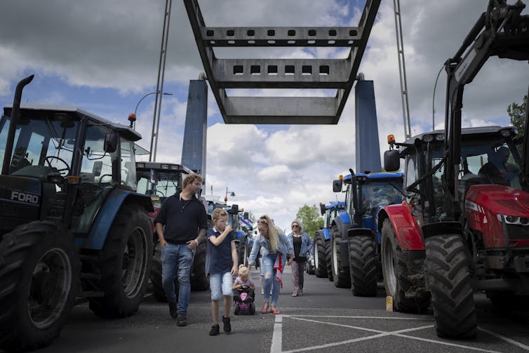 Protesters and their families walk down a draw bridge lined with tractors