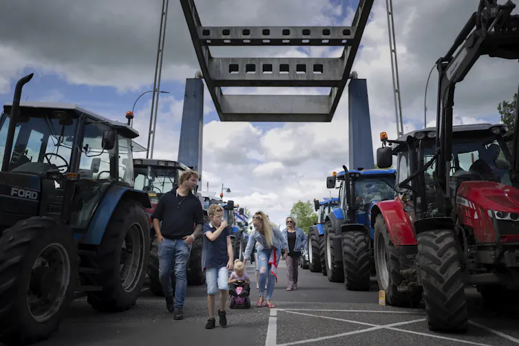 Protesters and their families walk down a draw bridge lined with tractors