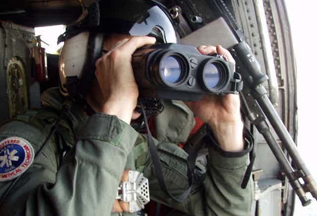 Person in military gear uses large binoculars