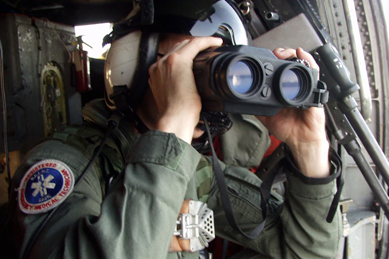 Person in military gear uses large binoculars