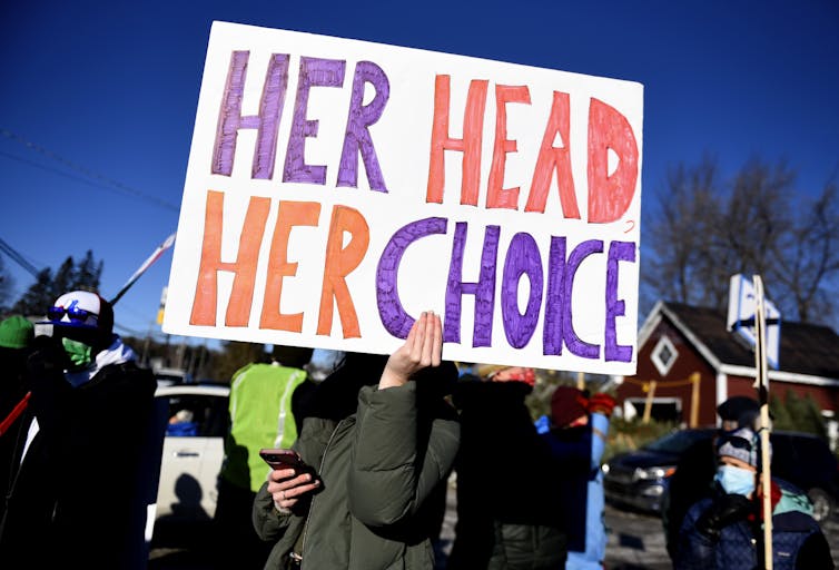 A protester waves a sign that reads Her Head, Her Choice
