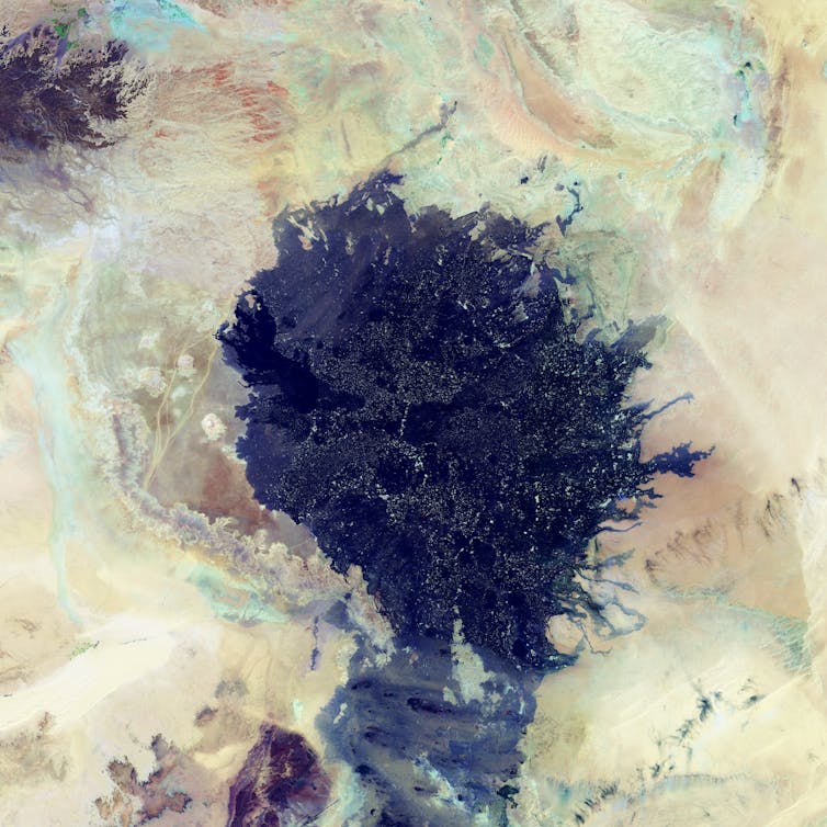 A black splatter of lava in surrounding sandy desert landscape