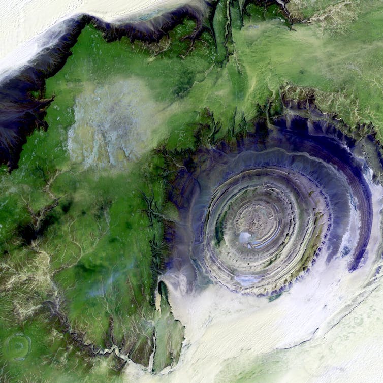 Concentric gray rocky rings surrounded by a green landscape from above