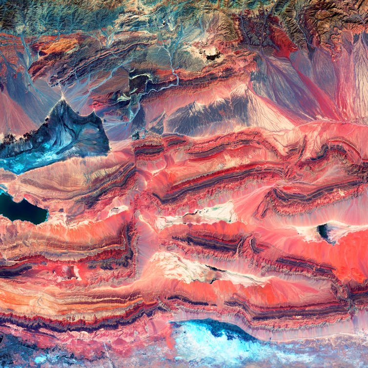 A landscape from above showing multi-coloured layers of rock that have been folded and broken apart