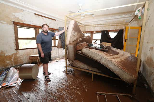 Man stand inside house wrecked by floodwaters