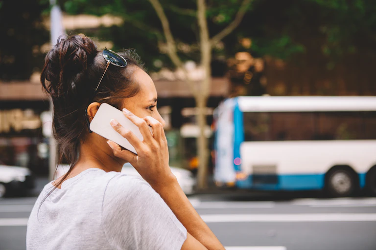 A First Nations person is on the phone while walking down a busy street.
