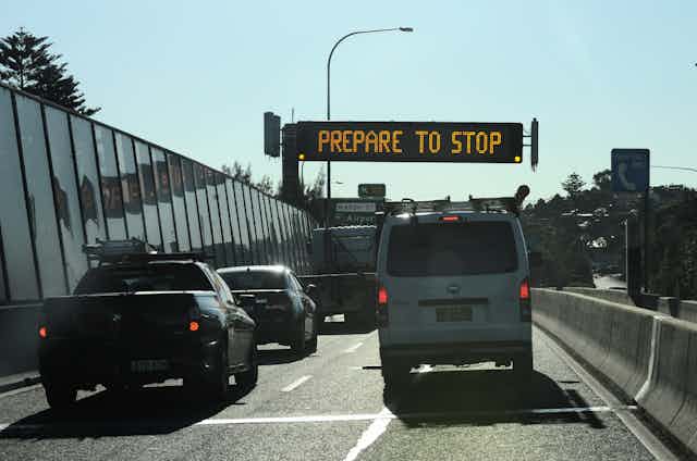 traffic queues in front of "prepare to stop" sign