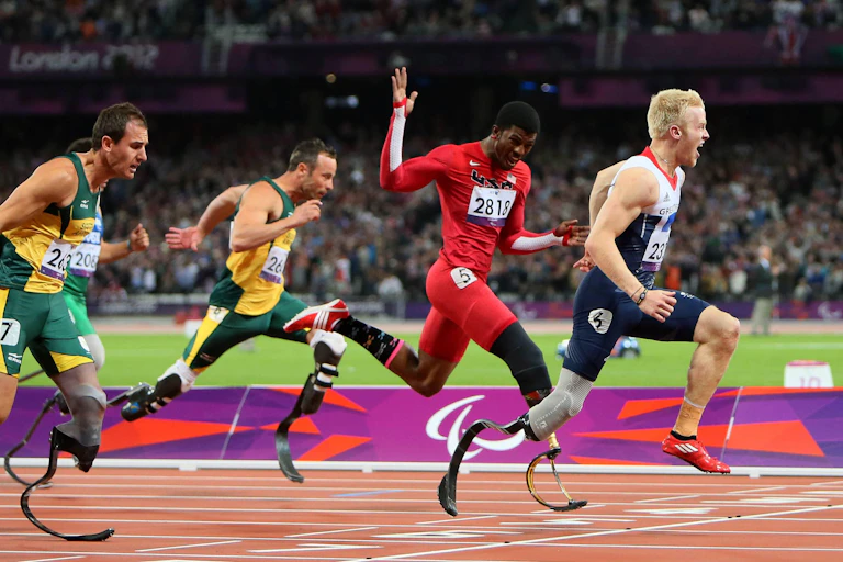A group of four paralympians race over the finish line at the London 2012 Paralympics.