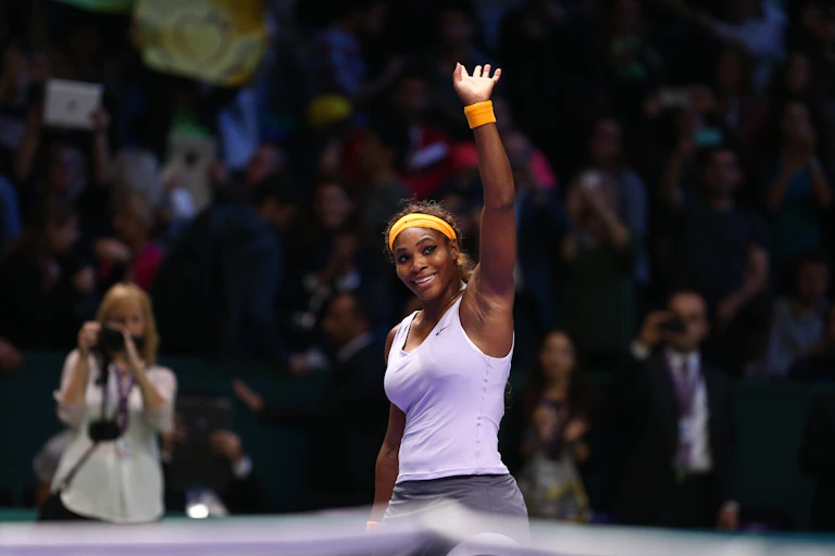 A picture of Serena Williams smiling and waving to the crowd during a tennis match.