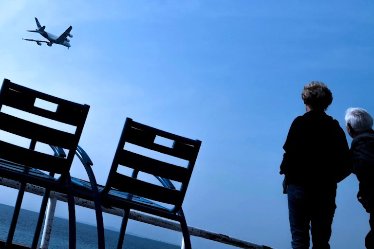 Deux personnes observent un Airbus A380 volant le long de la « promenade des Anglais», dans la ville de Nice sur la Côte d'Azur.
