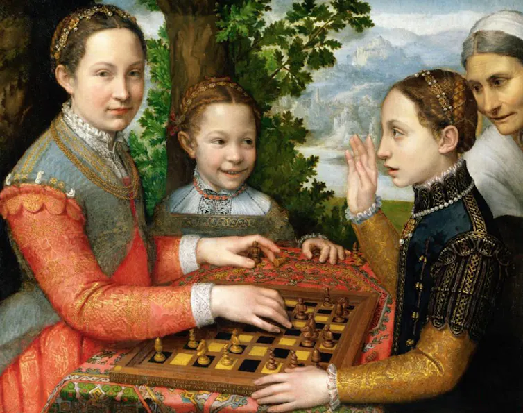 Dos mujeres juegan al ajedrez ante la mirada de una niña y una señora.