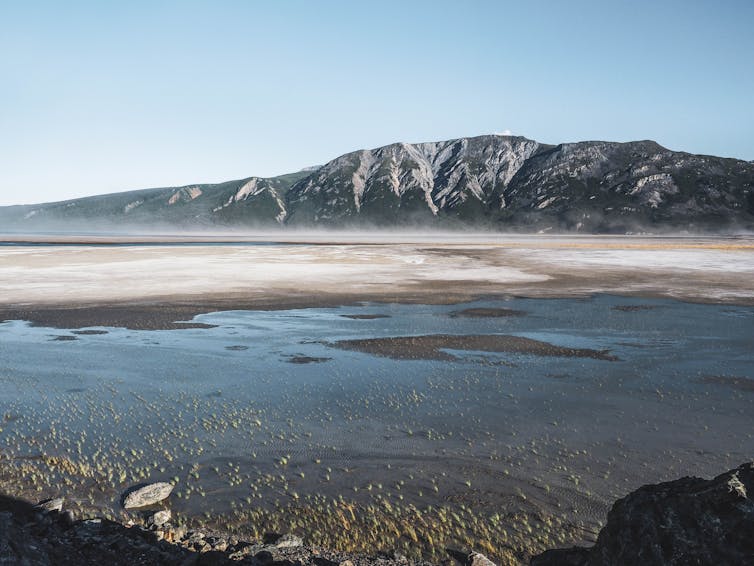 A lake is layered in mist with a mountain in the background