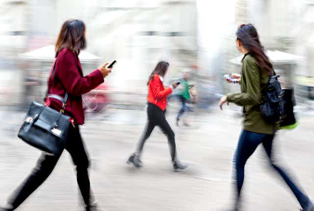People holding or looking at phones as they walk through the city