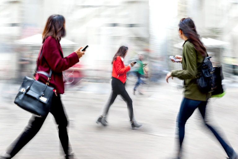 People holding or looking at phones as they walk through the city