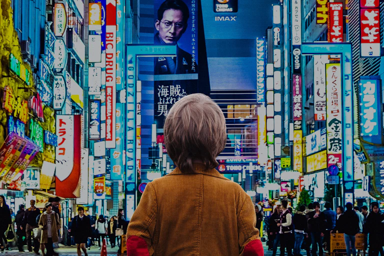 A child standing facing a busy Tokyo street, covered in screens.