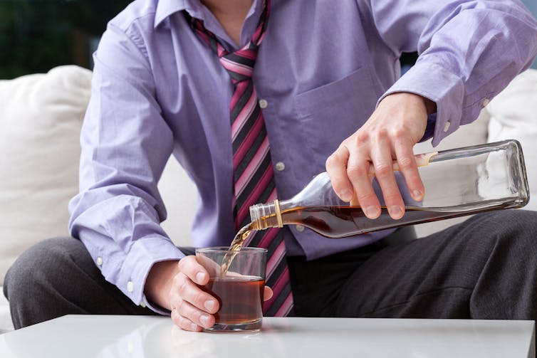 Man pouring a large glass of whisky.