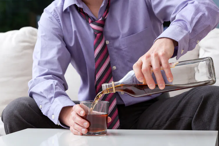 Man pouring a large glass of whisky.