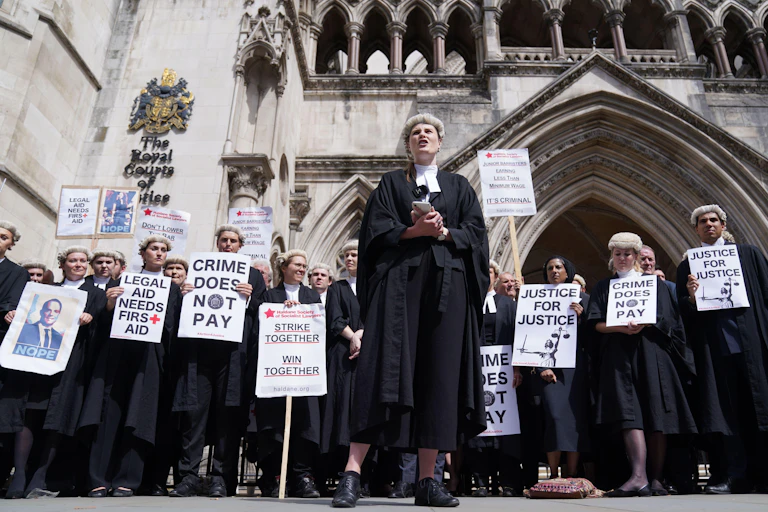 A group of barristers in wigs and gowns carrying strike signs