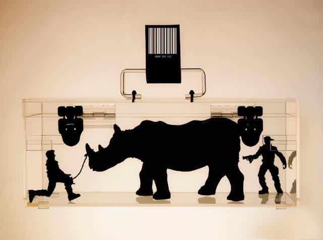 An x-ray image of a lockbox with a rhino and two armed men inside.