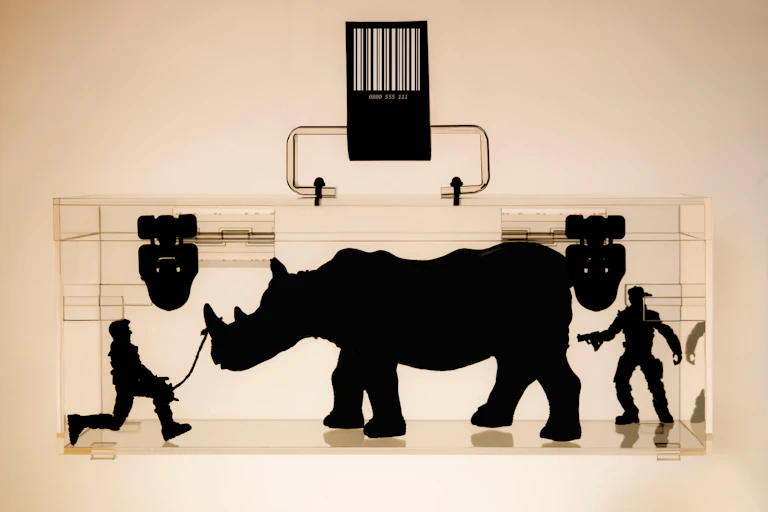 An x-ray image of a lockbox with a rhino and two armed men inside.