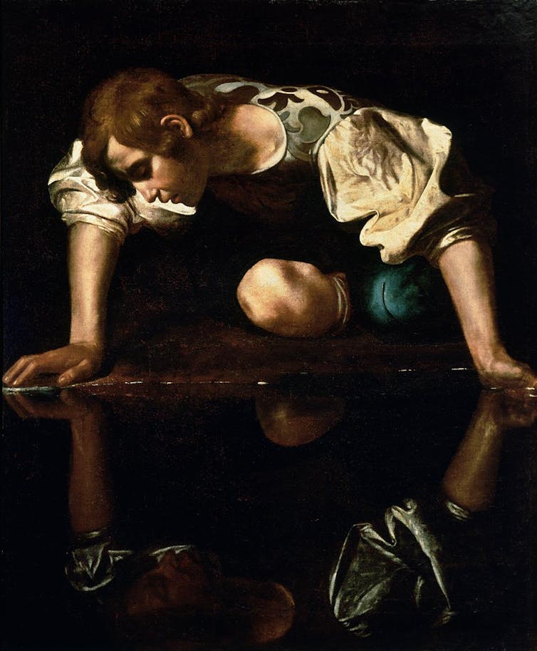 painting on young man looking at his own reflection