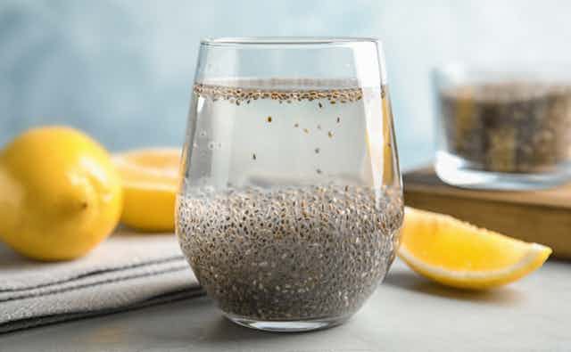 Glass with chia seeds, water, next to sliced lemon