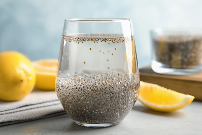 Glass with chia seeds, water, next to sliced lemon