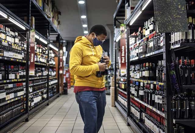 Un consommateur choisit des bouteilles d'alcool dans les rayons d'un magasin. 