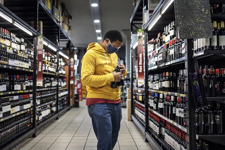 Un consommateur choisit des bouteilles d'alcool dans les rayons d'un magasin.