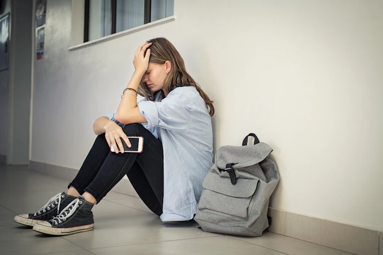 Jeune fille triste assise par terre.