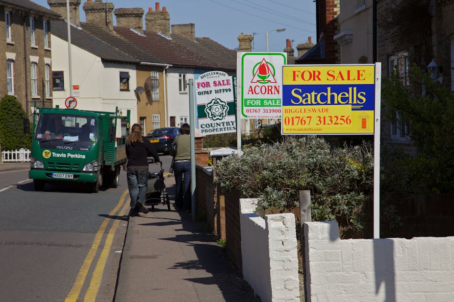 Woman walking down a street with lots of for sale signs