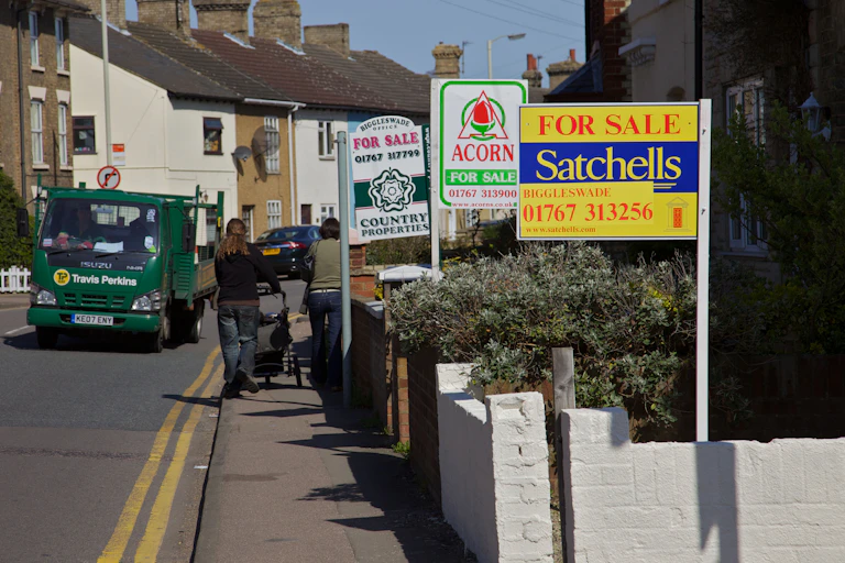 Woman walking down a street with lots of for sale signs