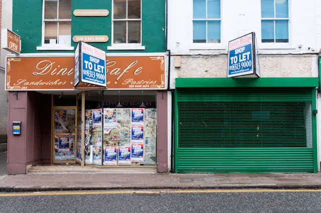 A row of boarded up high street shops with 'To Let' signs.