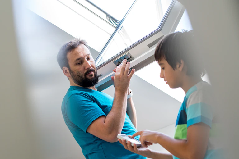 A father and son look at new windows. The boy is using a remote control device.