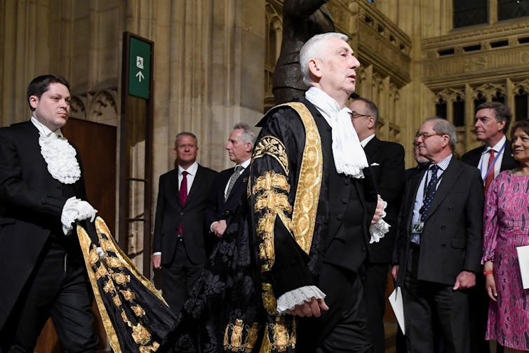 Lindsay Hoyle entering the House of Commons as a steward carries his robes behind him.