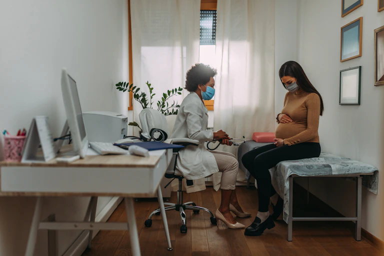 femme enceinte dans un bureau de médecin qui porte un masque