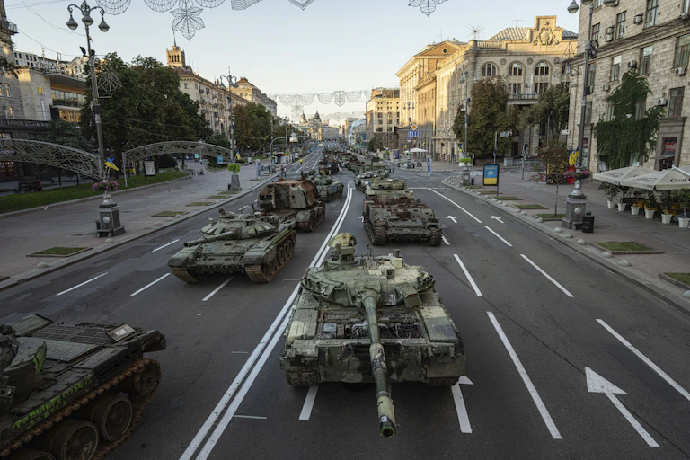 A line of destroyed military vehicles along a city street.