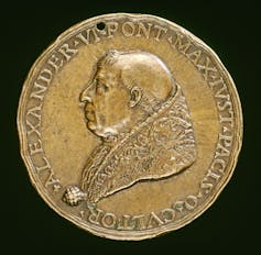 A bronze coin shows a profile portrait of a man in a heavy robe.
