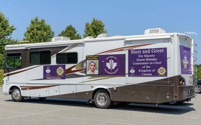 A mobile home with a woman's photo on the side and a sign that reads Meet and Greet Her Majesty Queen Romana Commander-in-Chief of the Kingdom of Canada.