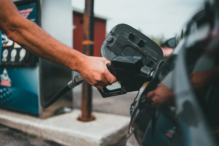 Hand holding fuel nozzle in car fuel spout